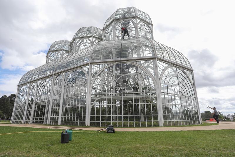 Com equipamentos de rapel, funcionário faz limpeza dos vidros da cúpula da estufa do Jardim Botânico